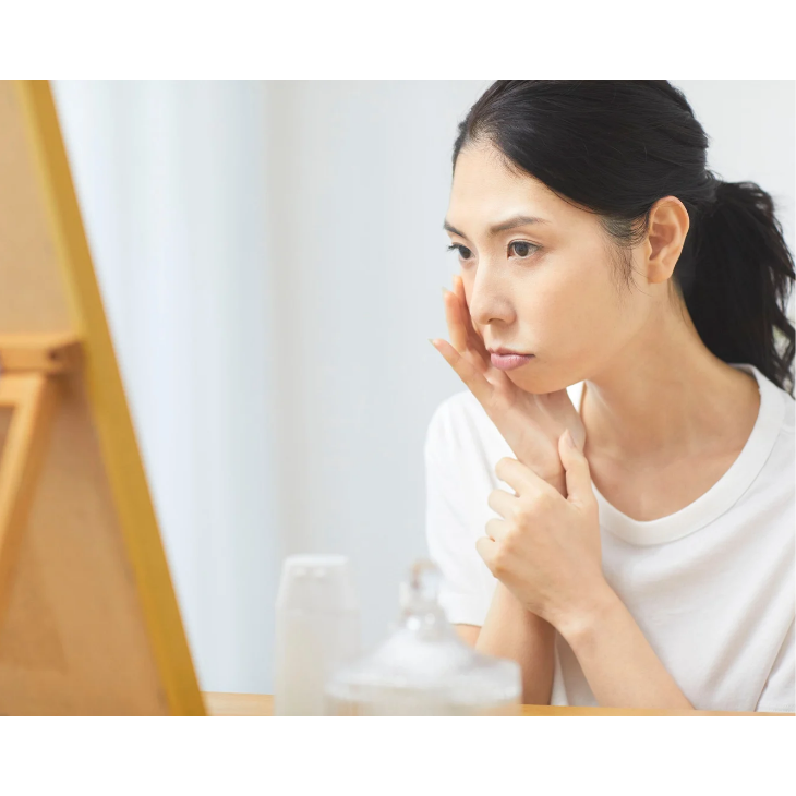 鏡を見てお肌に悩む女性